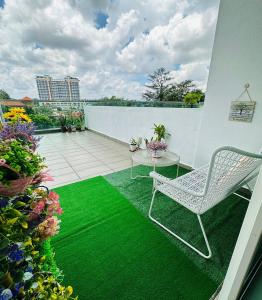 d'un balcon avec une chaise, une table et de l'herbe verte. dans l'établissement Paragon Residence 8-12pax-Big Balcony with BBQ, à Johor Bahru