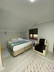 a white bedroom with a bed and a chair at Uzungöl Özkan Pansiyon in Uzungöl