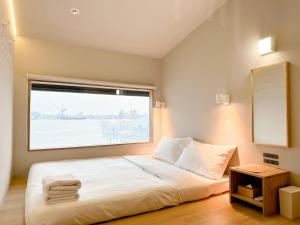 una camera da letto con un letto grande con una finestra di KW2 Hostel a Kaohsiung