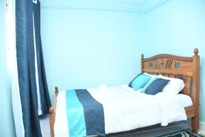 a bedroom with a wooden bed with blue and white pillows at Jiji Homes 1 Bedroom house with Wi-Fi king size bed. Free parking in Naivasha