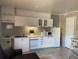 una cocina con armarios blancos y electrodomésticos blancos en Urmas Rehvid Holiday Home en Põlva
