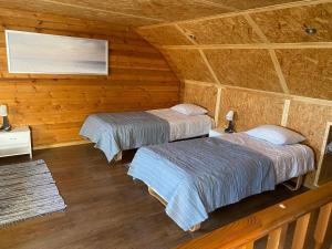 Duas camas num quarto com paredes de madeira em Urmas Rehvid Holiday Home em Põlva