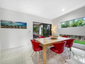 uma sala de jantar com uma mesa de madeira e cadeiras vermelhas em Casa Mia Retreat Luxury Family Home on Buderim em Buderim