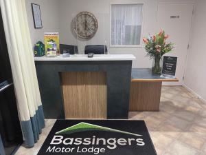 a reception desk in a office with a sign on the floor at Bassingers Motor Lodge in Levin