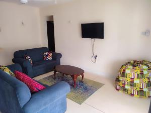 a living room with a blue couch and a tv at Vee's Villa in Kilifi