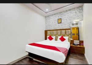 1 dormitorio con 1 cama grande con almohadas rojas en HOTEL SAROVAR INN, en Ahmedabad