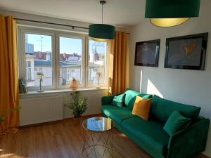 ein Wohnzimmer mit einem grünen Sofa und einem Fenster in der Unterkunft Apartament Pułaskiego 11m8 - Centrum Sopotu 1 min do Monciaka in Sopot