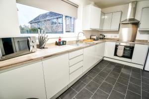 a kitchen with white cabinets and a window at Dalkeith House By Horizon Stays in Hartlepool