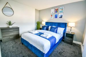 a bedroom with a blue bed and a mirror at Dalkeith House By Horizon Stays in Hartlepool