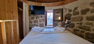 a bedroom with a bed in a stone wall at Petromilos1920 in Zefiría