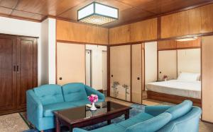 a living room with a blue couch and a bed at Hokke Lumbini in Rummindei