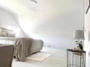 Casa Mina في Ferihaza: غرفة نوم بيضاء مع سرير وطاولة جانبية
