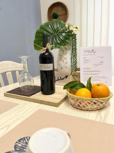 a bottle of wine and a basket of oranges on a table at Wanderlust Guesthouse in Lamezia Terme