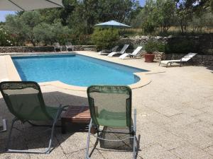 a pool with chairs and a table and an umbrella at Le Verger in Gordes