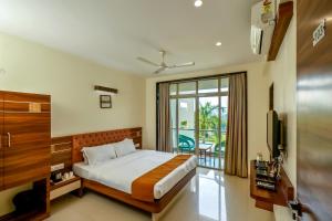 ein Schlafzimmer mit einem Bett und einem großen Fenster in der Unterkunft Hotel Sadhana Executive in Dapoli