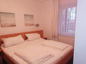een slaapkamer met een bed met witte lakens en een raam bij Ostseetraum in Ostseebad Koserow +14 foto's
