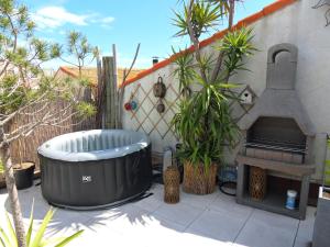 セットにあるSETE BELLE MAISON DE VILLE 121 m2 A 2 mn DE LA PLAGE AVEC JACUZZIのホットタブ(植物のあるパティオに座る)