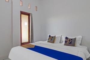 a bed with blue and white pillows on it at SPOT ON 92498 Fanni Homestay in Pekanbaru