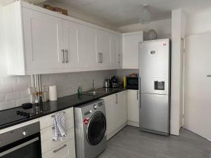 een keuken met witte kasten en een wasmachine en droger bij 1 Bedroom apartment - City of London in Londen