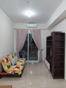 a living room with a couch and a window at Apartment Podomoro City Deli Medan in Medan