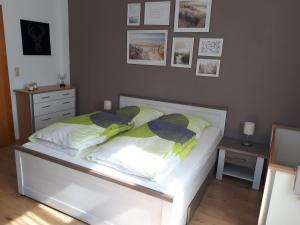 a bedroom with a white bed with pictures on the wall at Ferienwohnung auf einem Gutshof in Nordenham