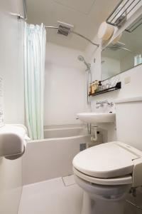 bagno bianco con servizi igienici e lavandino di Hotel Oak Shizuoka a Shizuoka