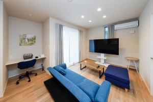 un soggiorno con divano blu e TV a schermo piatto di Higashi Komagata House a Tokyo