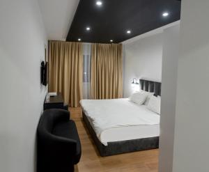 a bedroom with a white bed and a black chair at Hotel Beograd Struga in Struga