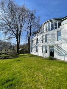a large white building with a grass field in front of it at The Coffee Jacket Apartment in Chemnitz