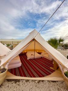 米茨佩·拉蒙的住宿－KARMEI NEGEV - מתחם גלמפינג ואטרקציות מבית גלובל גלמפינג，白色的帐篷,有红色和白色条纹地毯