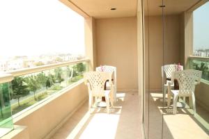 a balcony with white chairs and a large window at Al Manar Grand Hotel Apartment in Dubai