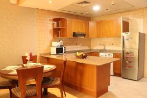 a kitchen with a table and a refrigerator at Al Manar Grand Hotel Apartment in Dubai