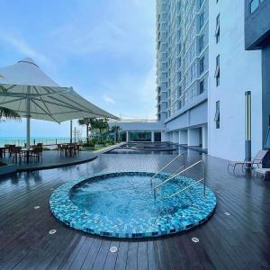 a swimming pool in a building with an umbrella at 4-6pax Seaview Condo 5min Kuantan town in Kuantan