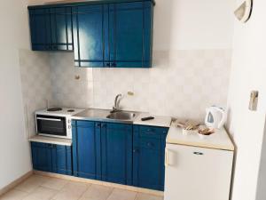 una cucina con armadi blu, lavandino e frigorifero di Aigaio studios & rooms ad Azólimnos