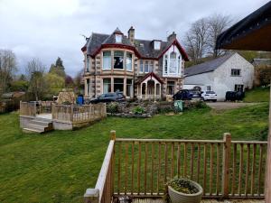 une grande maison avec une clôture devant elle dans l'établissement Strathview, à Strathpeffer