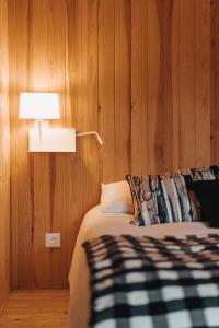 a bedroom with a bed with a lamp and wooden walls at le chalet de Plainpalais in Les Déserts