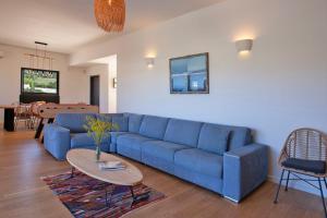 un soggiorno con divano blu e tavolo di Villa avec piscine bbq pétanque Calme à 5km de la plage de sable de Calvi a Calenzana
