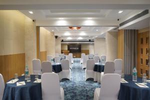 a conference room with tables and chairs and a screen at Cocoon Hotel in Pune