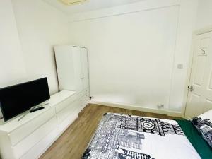 um quarto branco com uma cama e uma televisão em Cozy apartment in Hampstead Heat em Londres