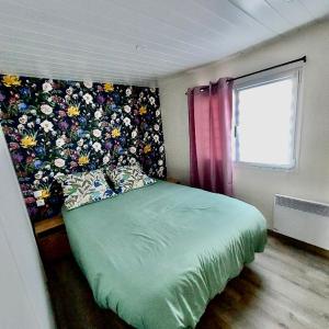 1 dormitorio con cama verde y pared de flores en Mammiehome - 6 places - Mimizan - Camping La Lande, en Mimizan