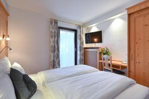 um quarto com uma cama, uma secretária e uma janela em Hotel Alpenstuben em Hohenschwangau
