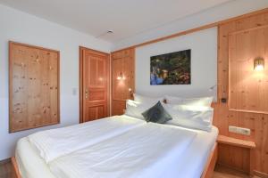 a bedroom with a large white bed with wooden cabinets at Hotel Alpenstuben in Hohenschwangau