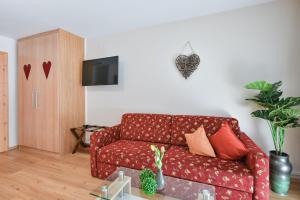uma sala de estar com um sofá vermelho e uma televisão em Hotel Alpenstuben em Hohenschwangau