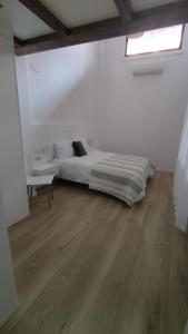 a white bedroom with a bed and a table at vivienda turística los Robles in Tudela