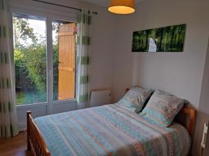 a bedroom with a bed and a large window at Les Fortelles in Châtillon-sur-Broué