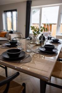 a wooden table with black plates and glasses on it at Charming 3-Bed House with 1 Parking space in Canterbury