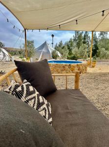米茨佩·拉蒙的住宿－KARMEI NEGEV - מתחם גלמפינג ואטרקציות מבית גלובל גלמפינג，一张沙发,坐在带桌子的帐篷下