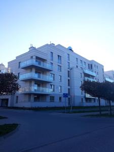 a large white apartment building with a parking lot at Apartament Przystań z tarasem in Giżycko