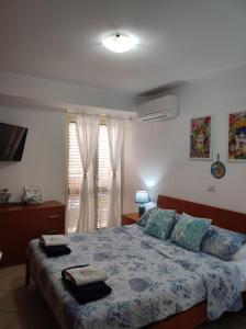 1 dormitorio con 1 cama con manta azul y ventana en Playa Bonita Relax House, en Scilla