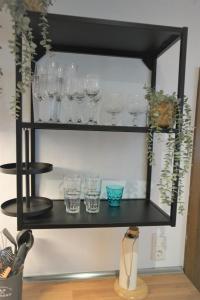 une étagère noire avec des verres et des plantes sur elle dans l'établissement Mill Valley Appart, à Coblence